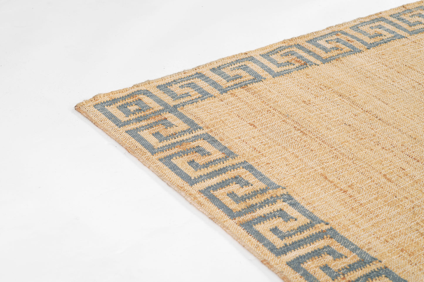 Beige woven rug with a blue Greek-key border along the edges and natural jute texture.