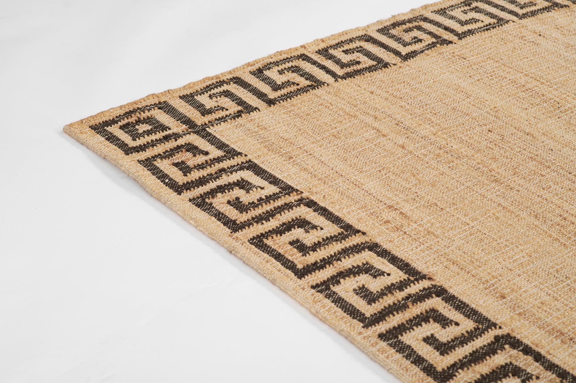 Beige jute rectangular rug with a black Greek key border and natural woven texture.