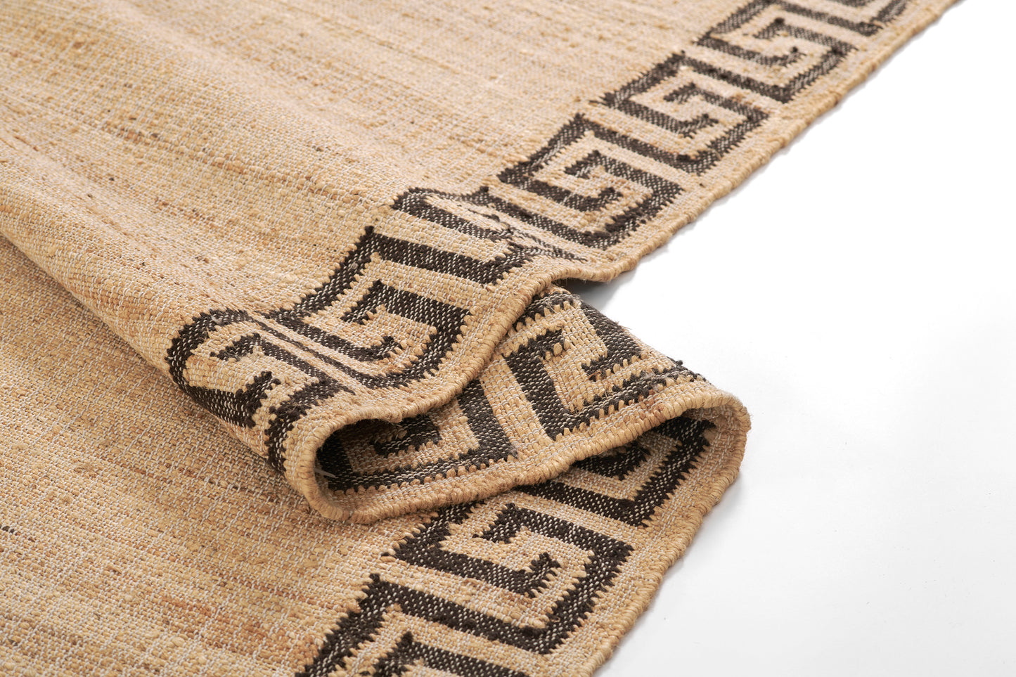 Beige woven rug with dark brown Greek-key border and rolled corner, natural jute texture.