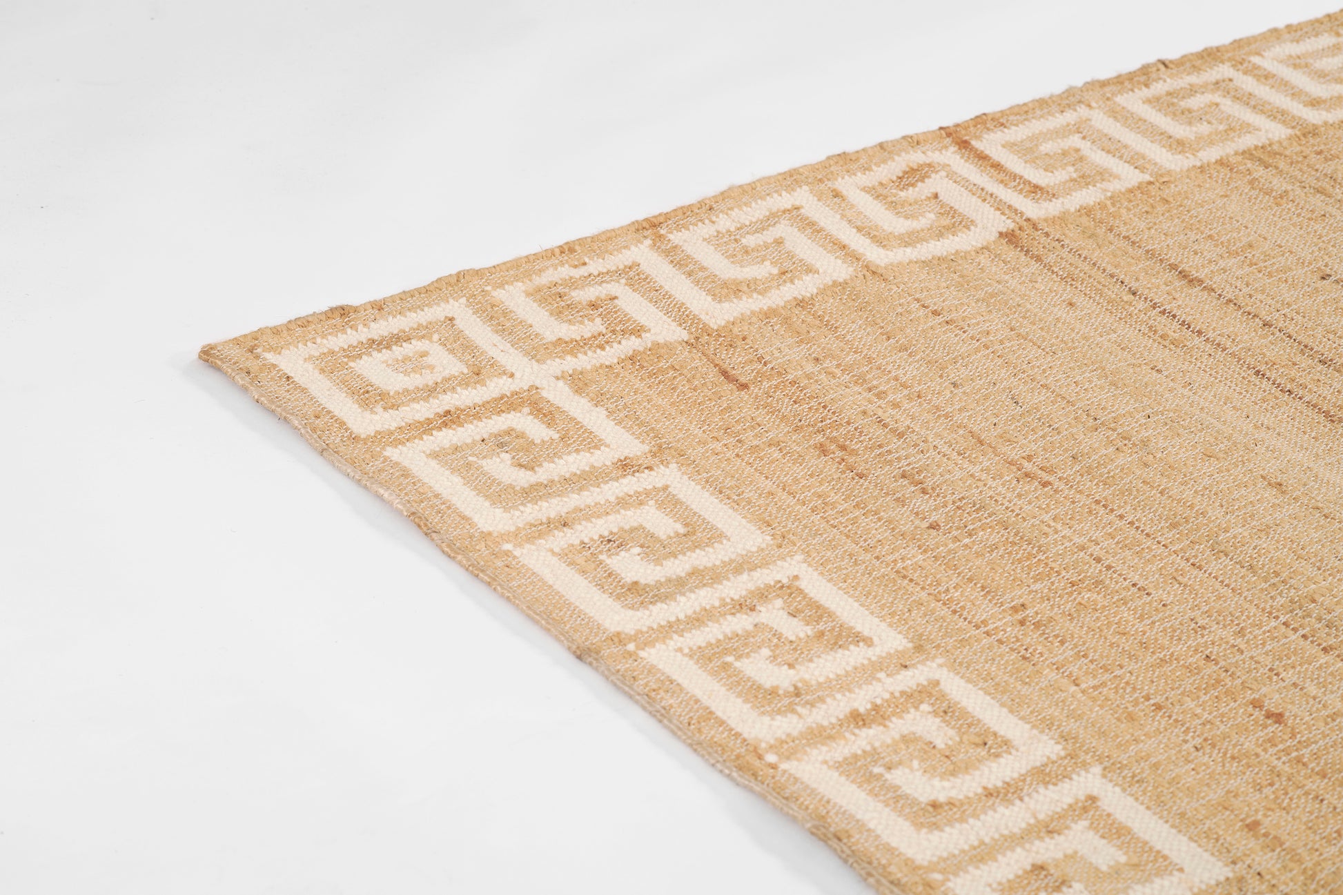 Natural jute rug with white Greek key border along edges, rectangular, rustic textured weave.