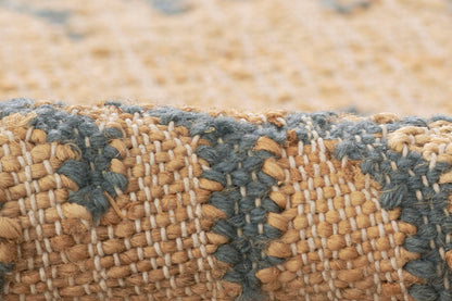 Handwoven jute rug with tan natural fibers and blue-gray stripes; textured, braided weave for coastal decor.