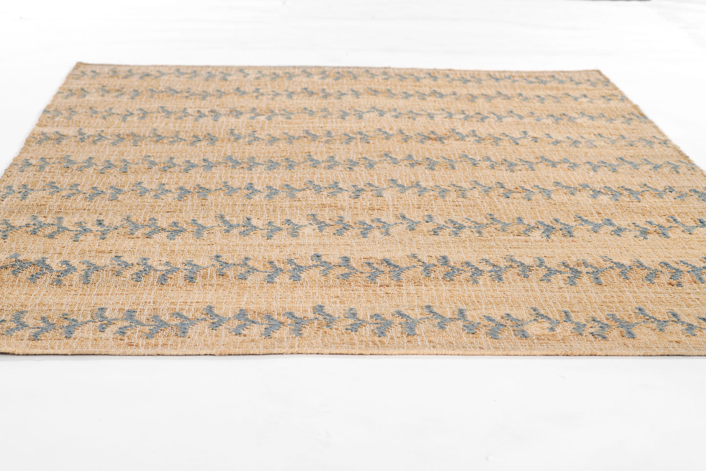Rectangular flat-weave rug in natural beige with blue geometric motifs; rustic jute texture.