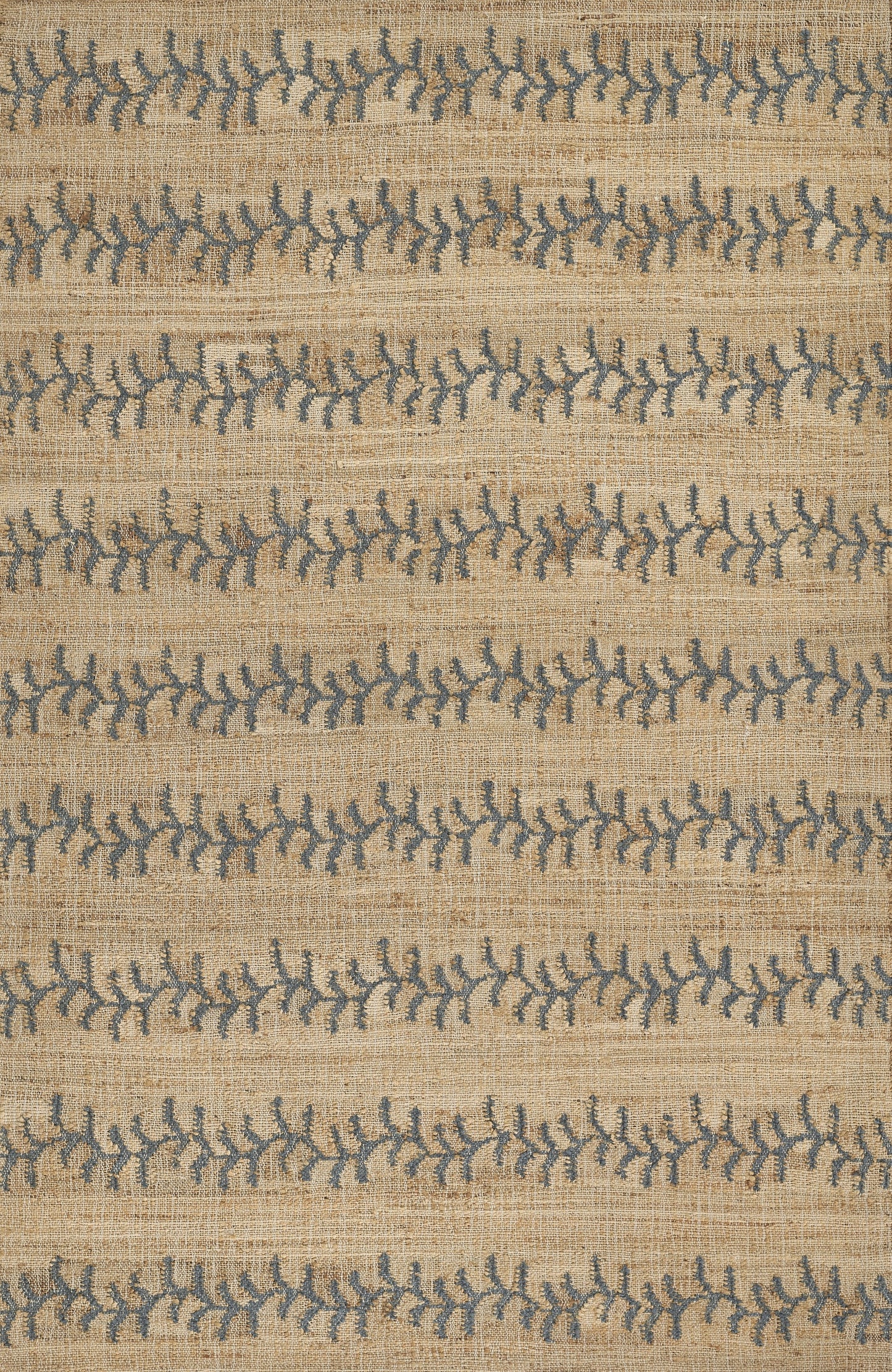 Beige woven rug with blue leafy branch motifs in horizontal stripes; natural fiber texture.