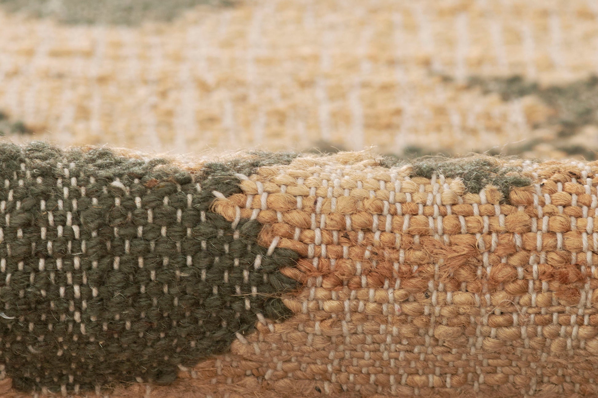 Close-up of a natural fiber woven rug in beige and charcoal tones with a textured flat-weave.