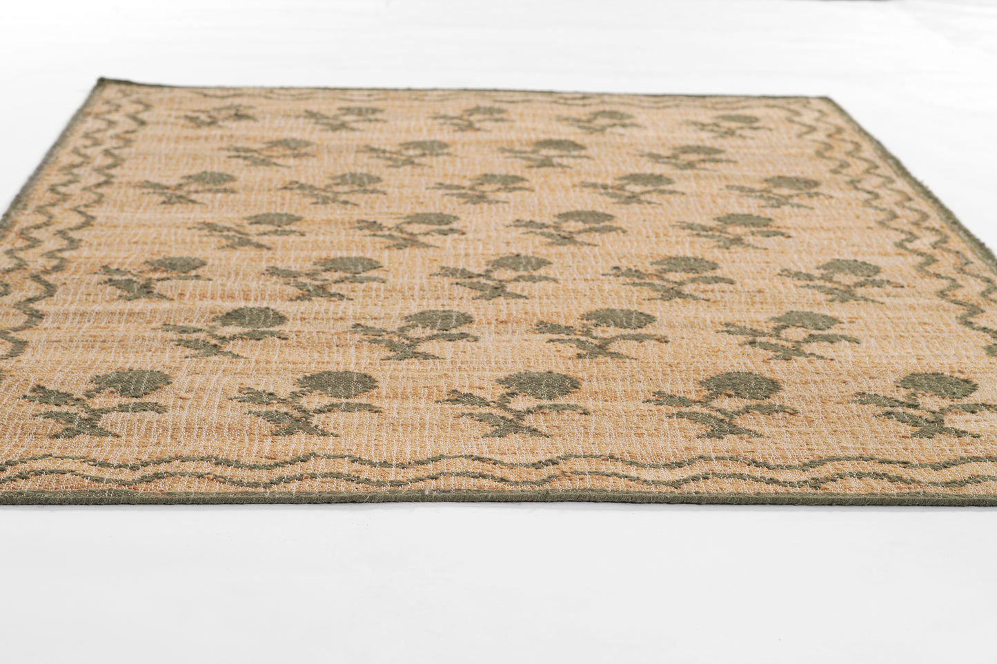 Rectangular natural beige jute rug with leaning flower pattern and woven border; boho-style.