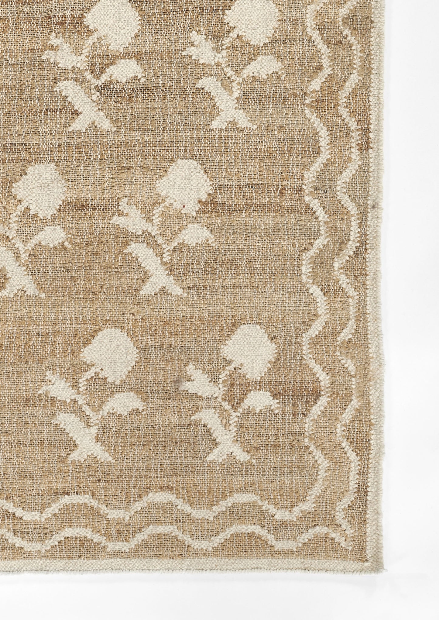 Beige jute rug with white floral damask motifs and scalloped wavy border.
