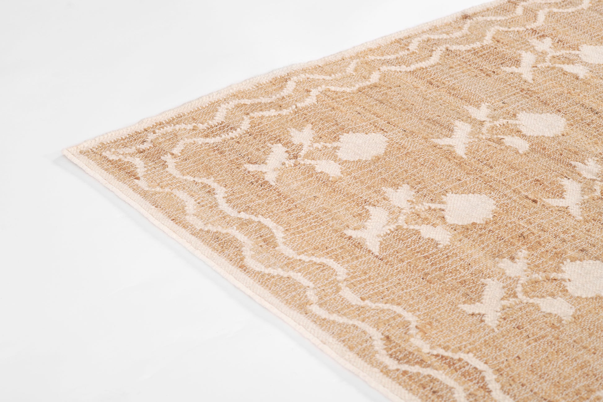 Beige rug with white botanical motifs and scalloped wavy border; soft textured, boho-chic decor.