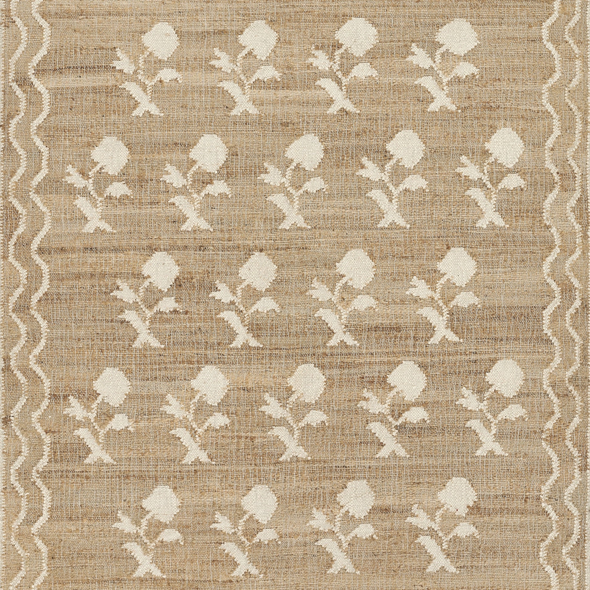 Natural jute rug with white embroidered flower motifs and wavy border, rustic boho style.