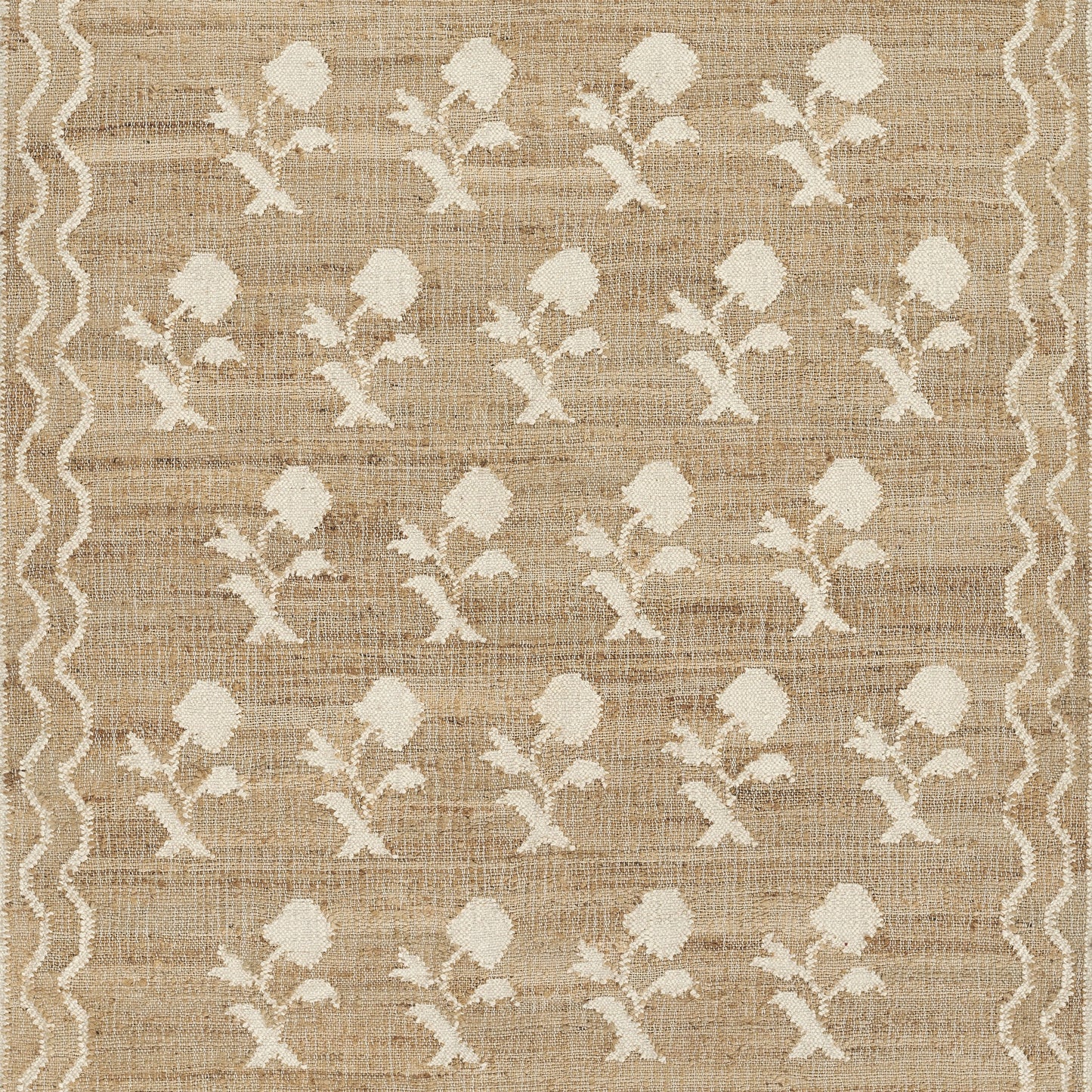 Beige jute rug with repeating cream floral motifs and a white wavy border along the sides.