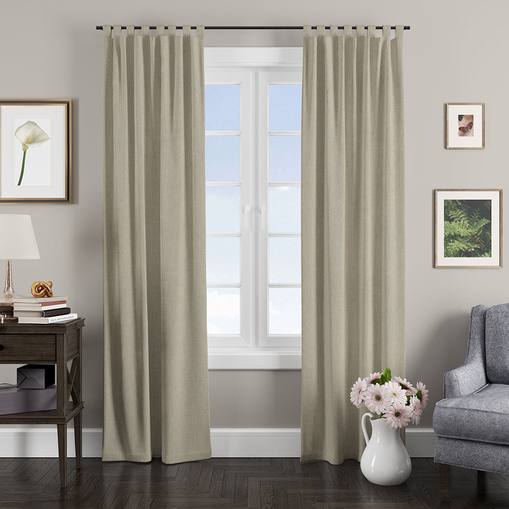 Taupe solid, textured fabric curtains on a black rod framing a white-paned window in a gray living room.