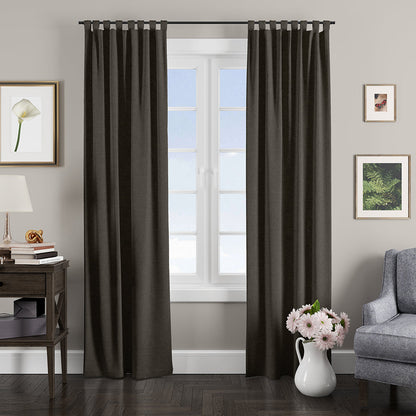 Dark charcoal grommet-top blackout curtains frame a bright window in a modern living room.