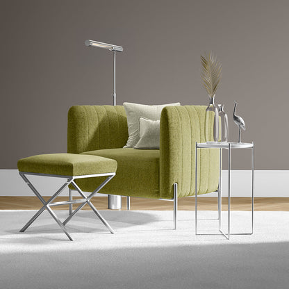 Olive-green textured sofa with matching ottoman, chrome X-leg base, and slim glass-top side tables in a modern living room.