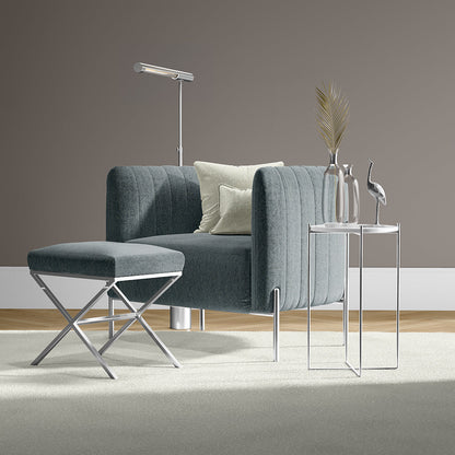 Blue-gray ribbed fabric armchair with matching ottoman and chrome legs, paired with glass side tables in modern living room.