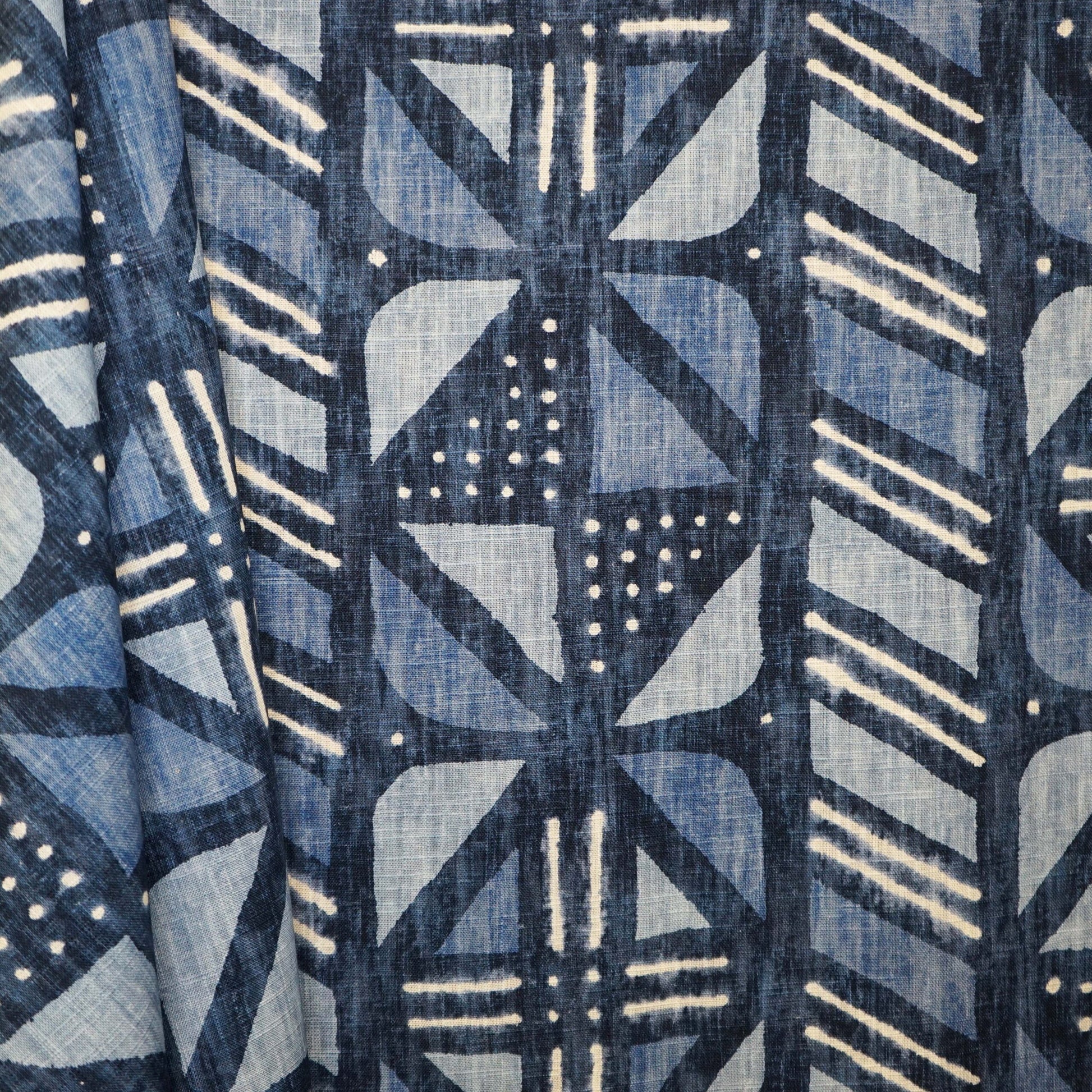 Blue geometric patterned fabric featuring diamond and stripe motifs in indigo tones; suitable for curtains or upholstery.