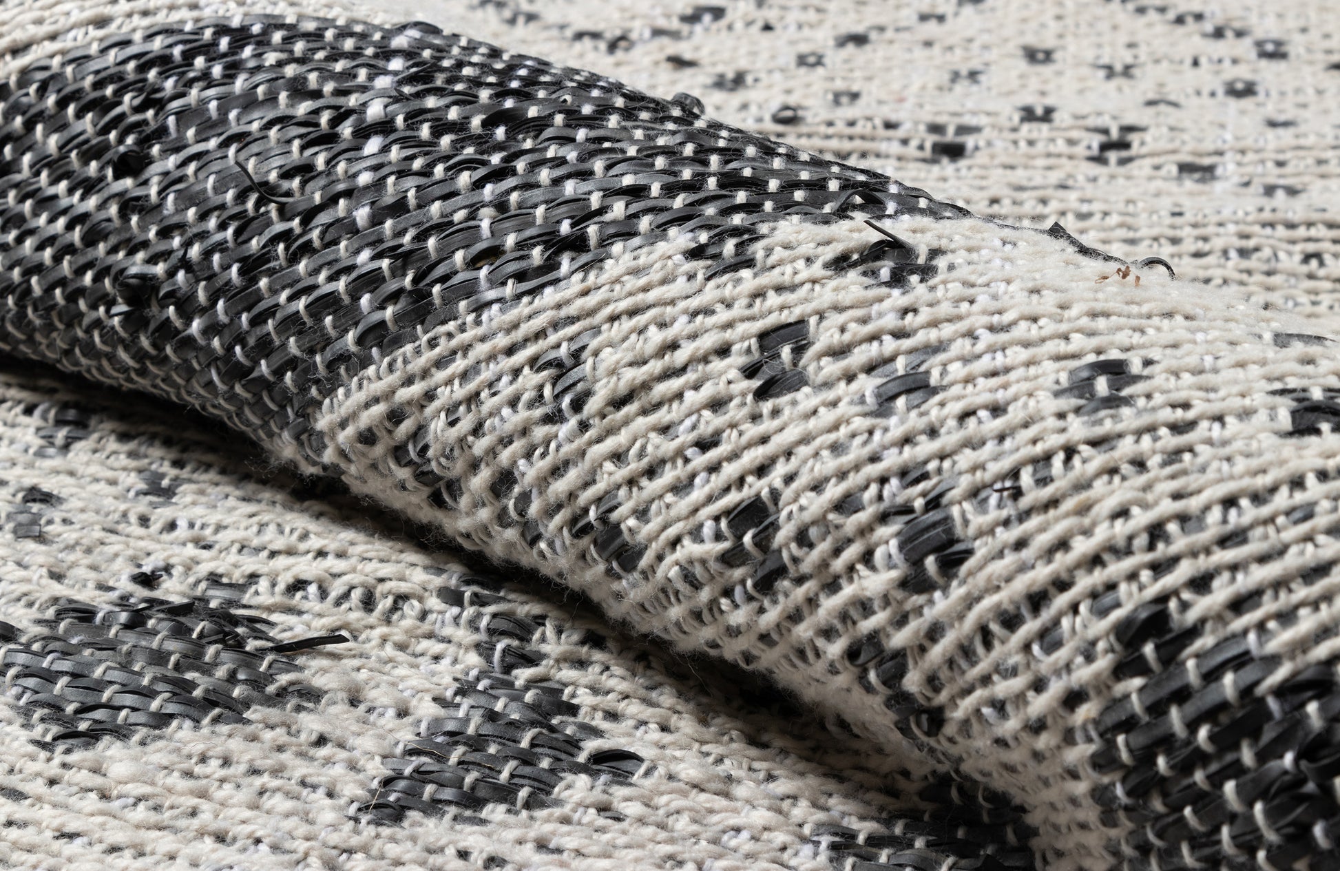 Folded black-and-cream woven rug with geometric pattern and chunky textured weave for modern boho home decor.