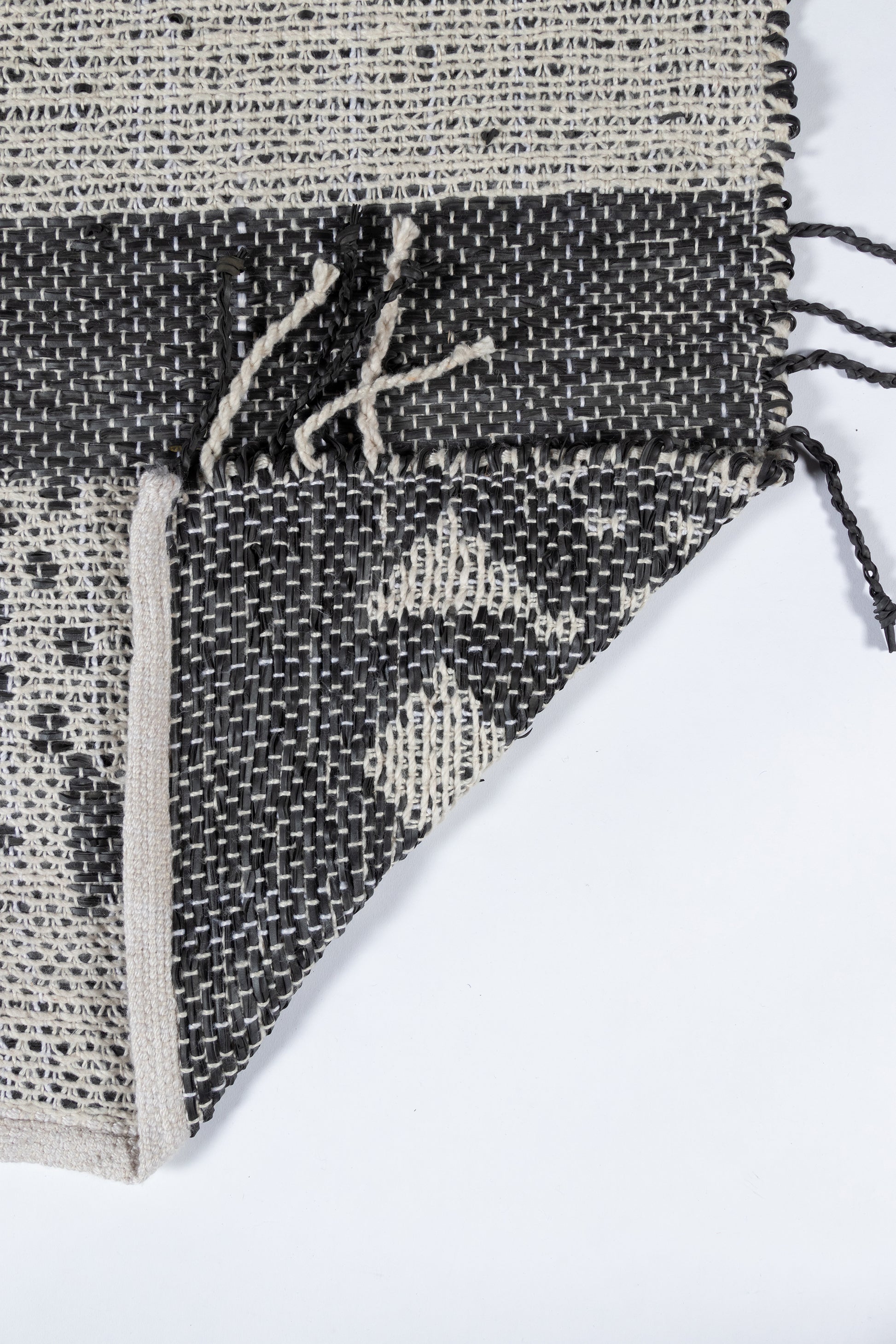 Handwoven black & ivory geometric rug with fringe, triangle pattern.