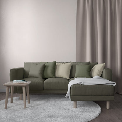 Olive green fabric sectional sofa with matching cushions and a chaise, wooden legs, a round wood coffee table, and a light throw.
