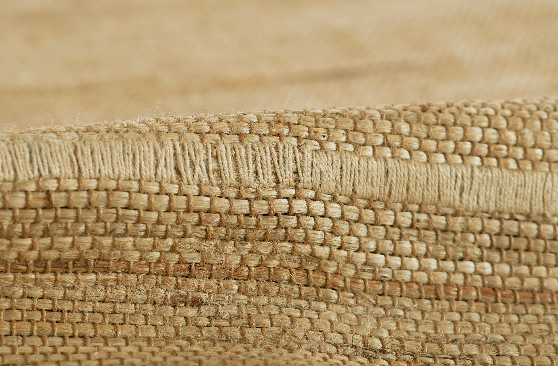 Natural beige woven rug close-up with chunky braided texture in jute fiber