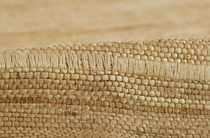 Natural palm fiber weave rug close-up with beige braided edge, rustic coastal style.