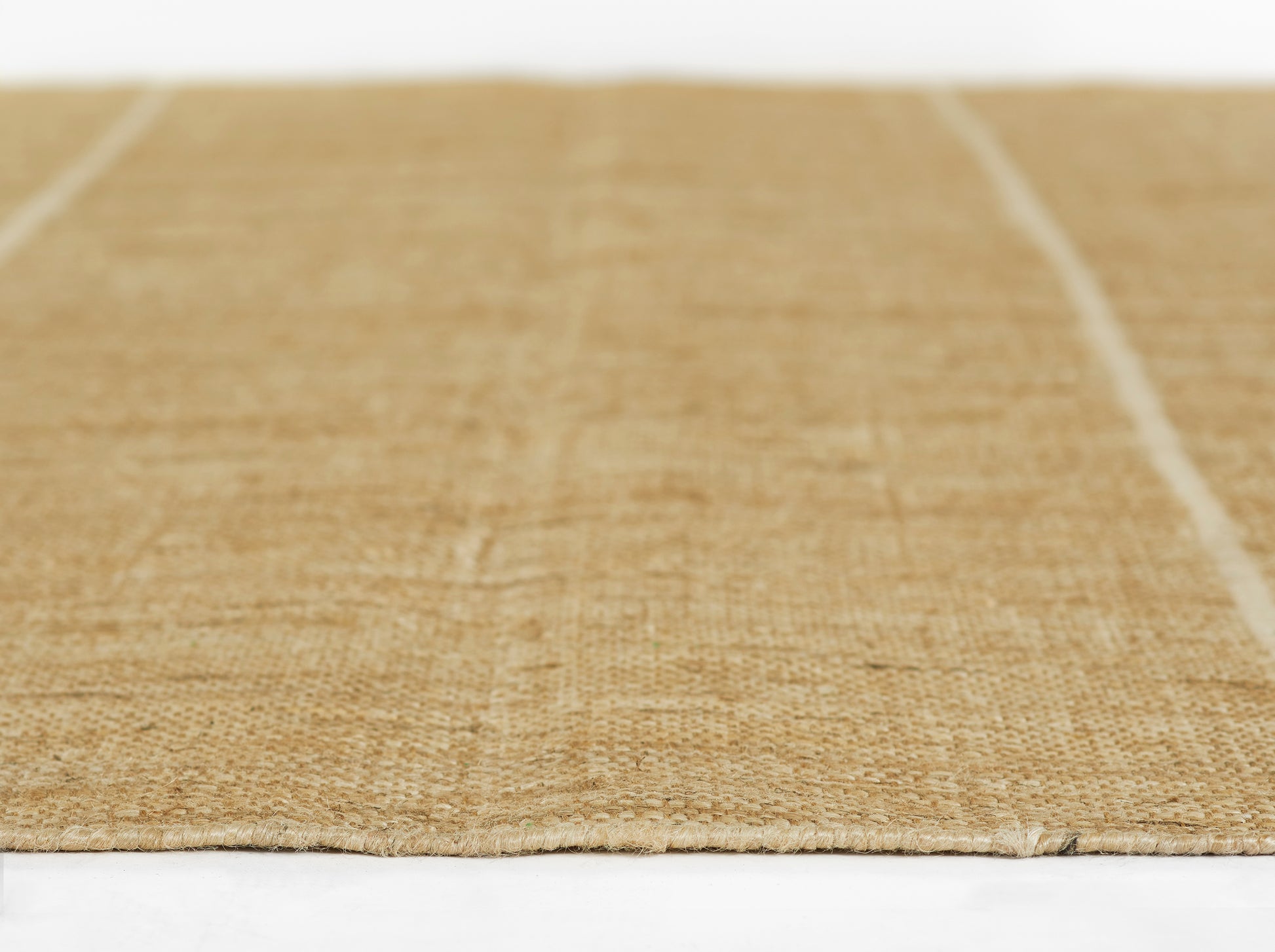 Natural jute rug in warm beige with a flat, woven texture; rectangular rustic mat for living room or entryway.