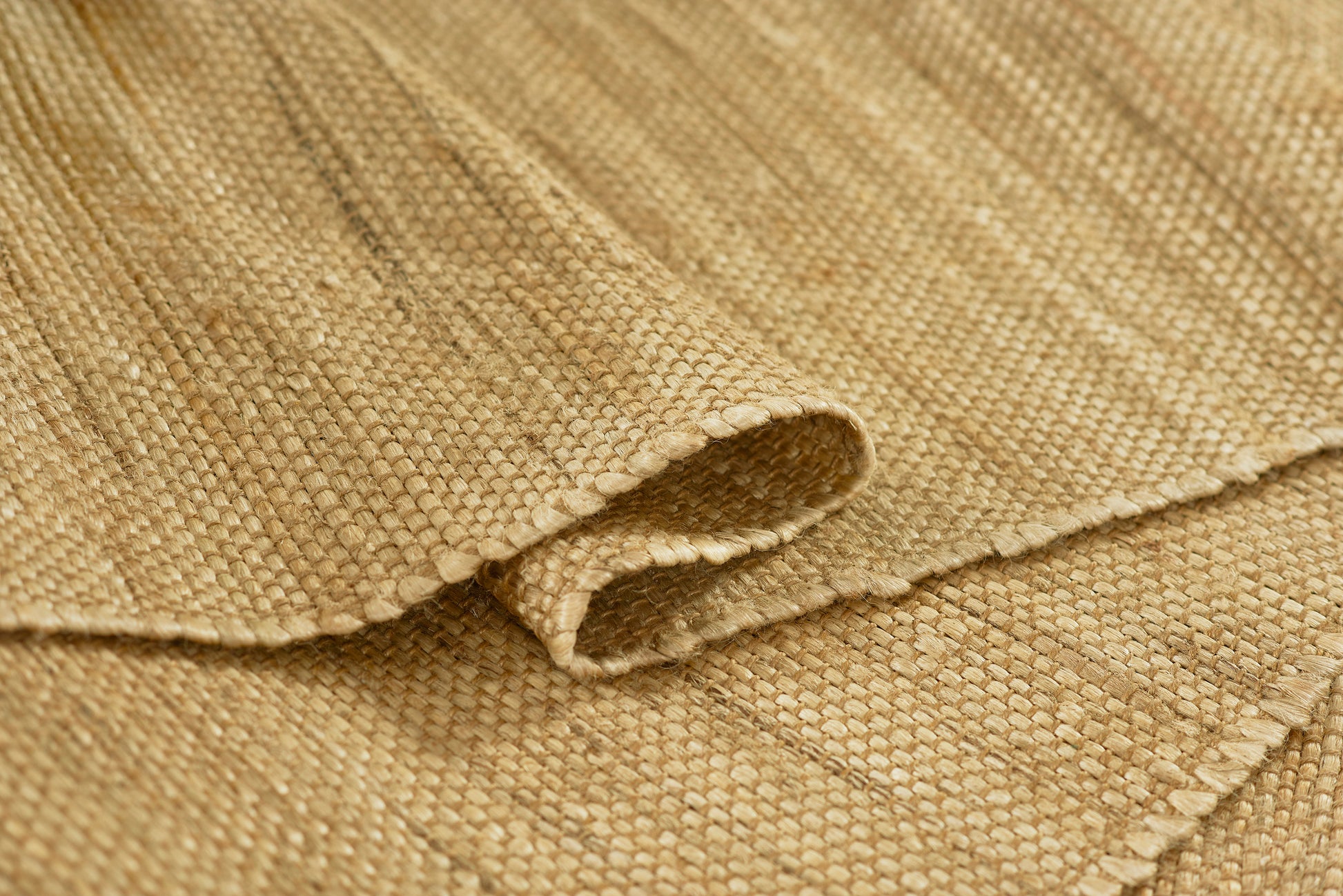 Natural beige burlap fabric close-up with a coarse weave and folded edge.