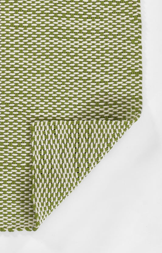 Green and white woven rug with a tight grid pattern and folded corner.