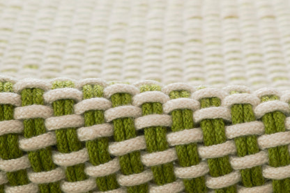 Close-up of a paracord-style white and olive-green braided rug with chunky woven texture.