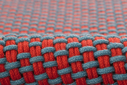 Close-up of red and blue paracord woven fabric with interlaced cord pattern.