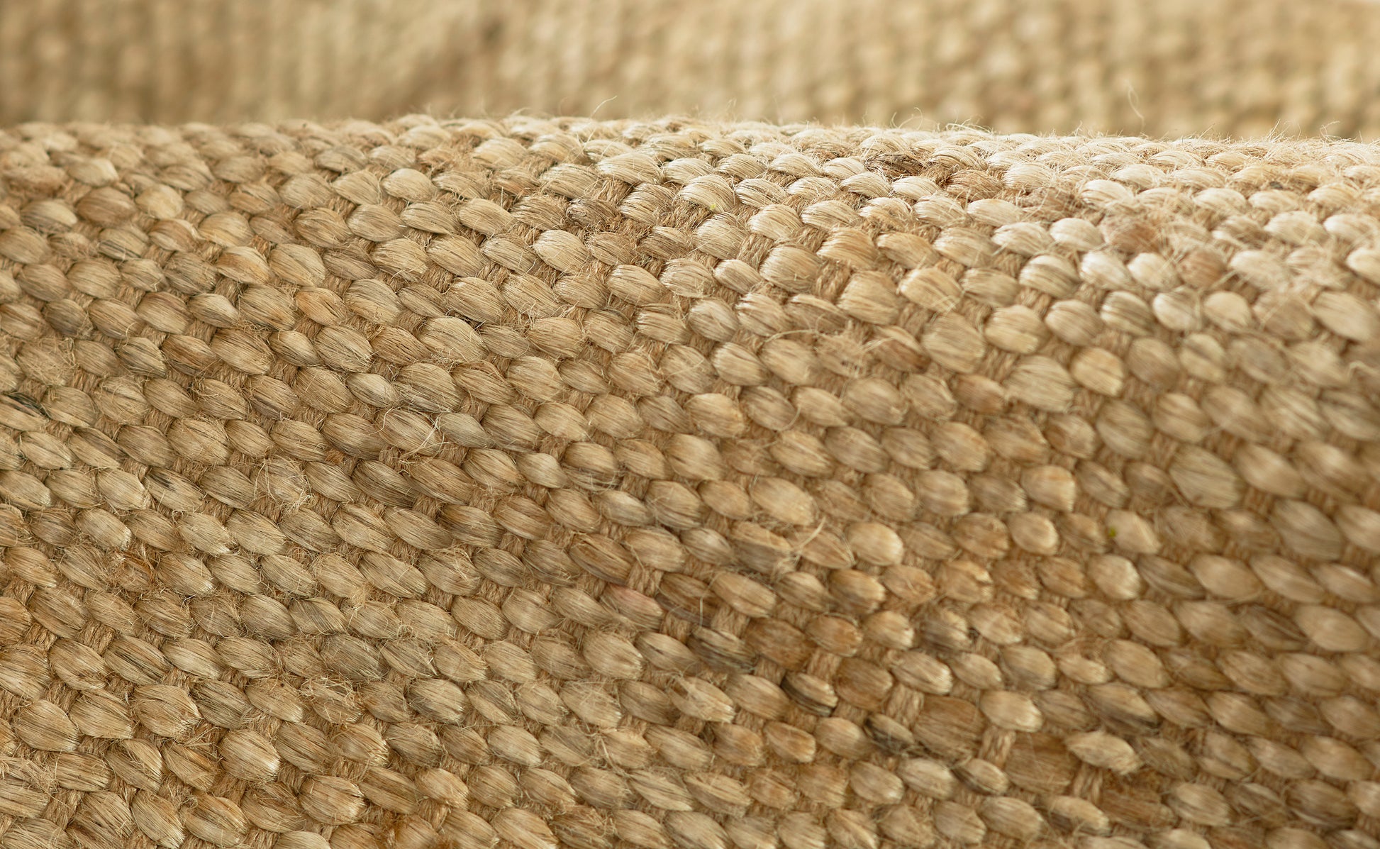 Close-up of natural beige jute fabric weave; burlap-like texture visible on a rug runner.