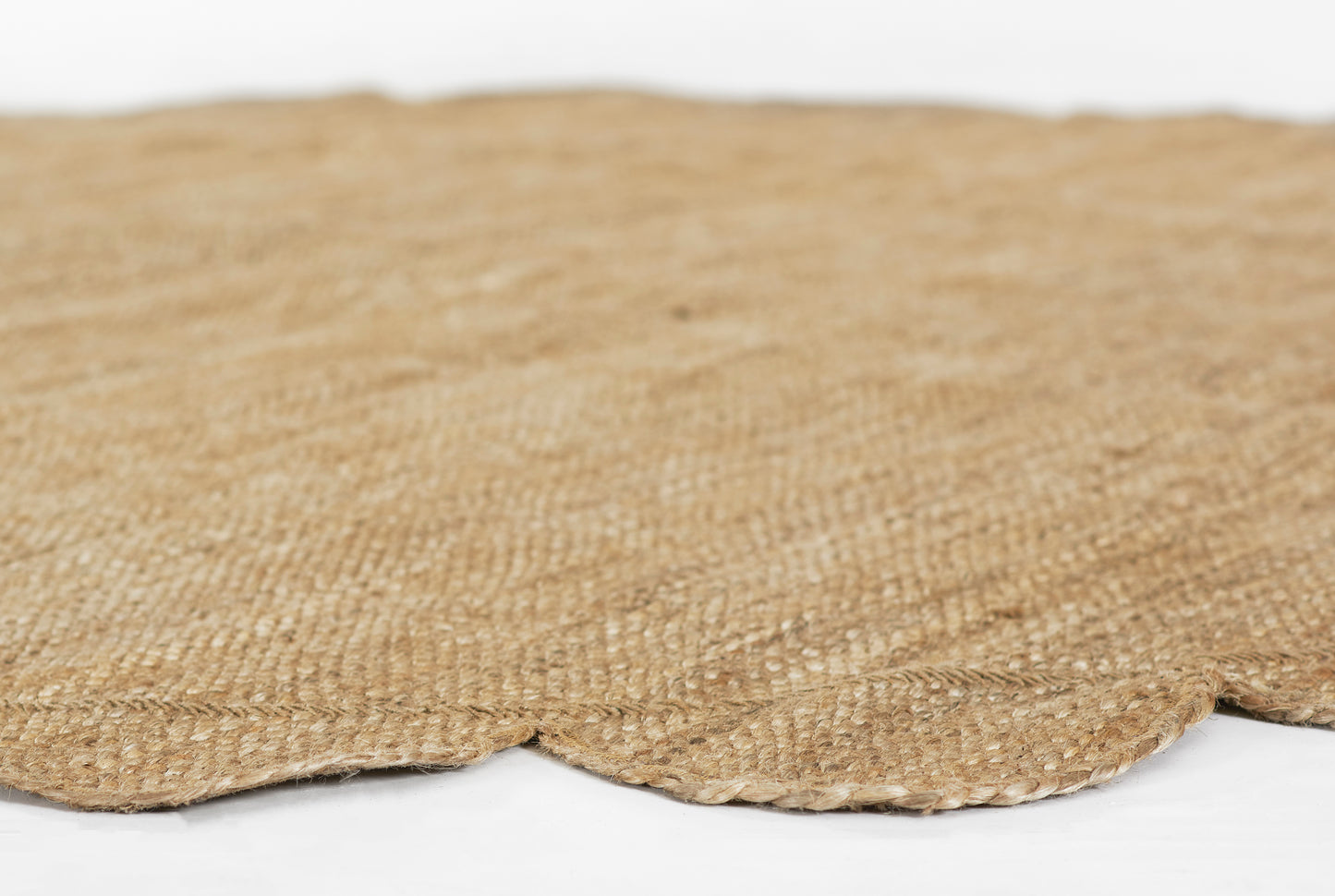 Natural jute round rug with scalloped edge & textured woven fibers in beige.