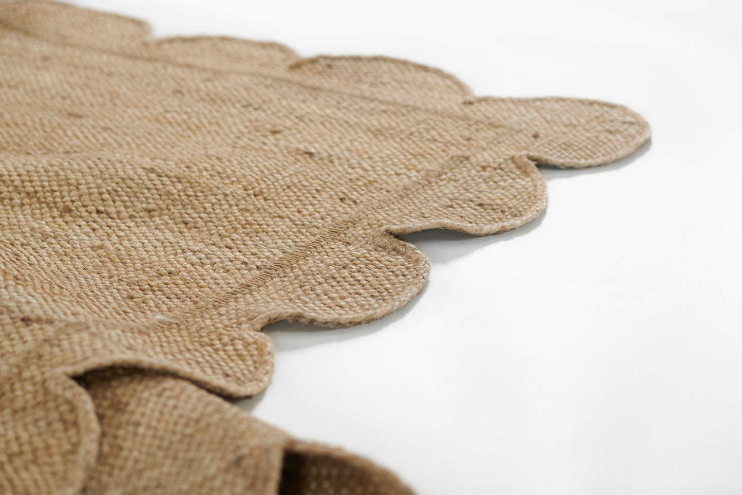 Natural burlap rug with scalloped edges and rough woven texture, 5' x 8'.