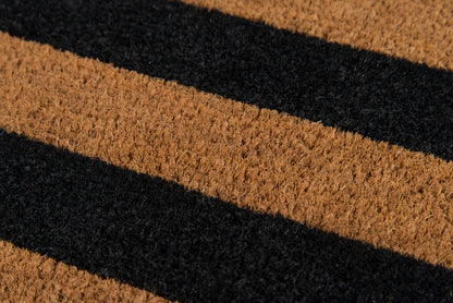 Diagonal brown and black striped coir doormat with textured fibers for front-door use.