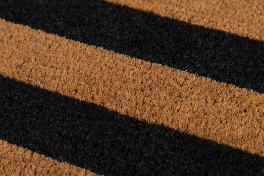 Diagonal brown and black striped coir doormat with textured fibers for front-door use.