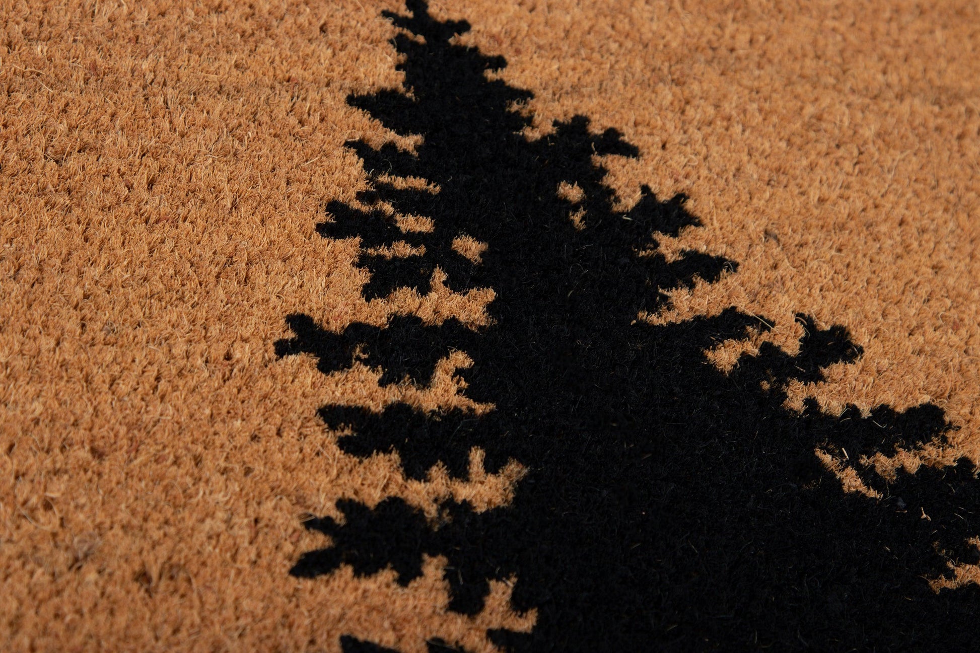 Natural coir rug with a black evergreen tree silhouette on tan textured background.