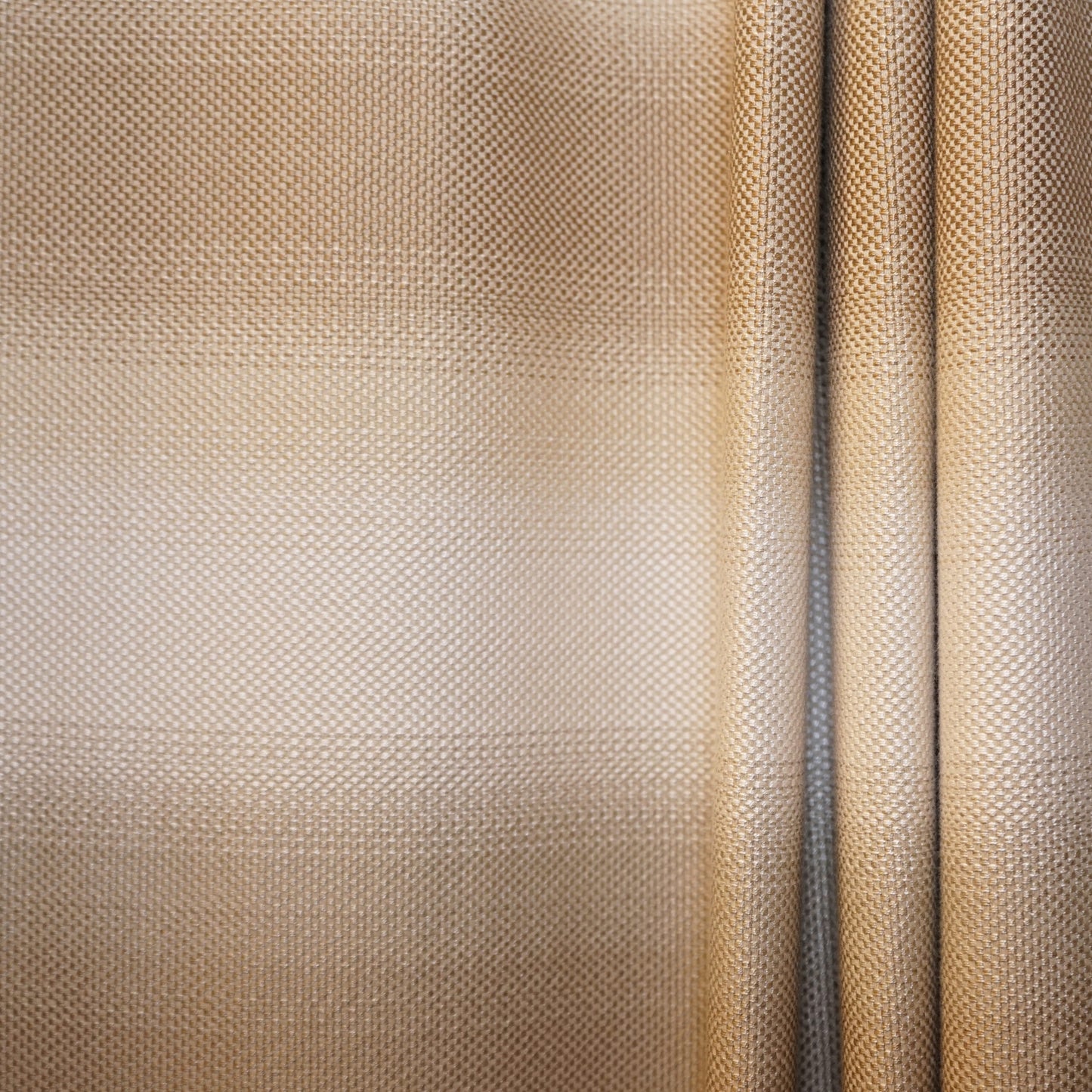 Beige-gold woven fabric close-up, textured dot pattern, draped panels with a vertical seam.