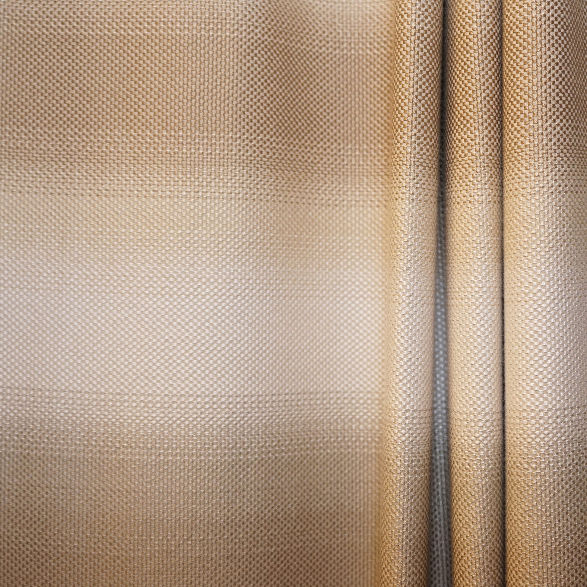 Beige-gold woven fabric close-up, textured dot pattern, draped panels with a vertical seam.
