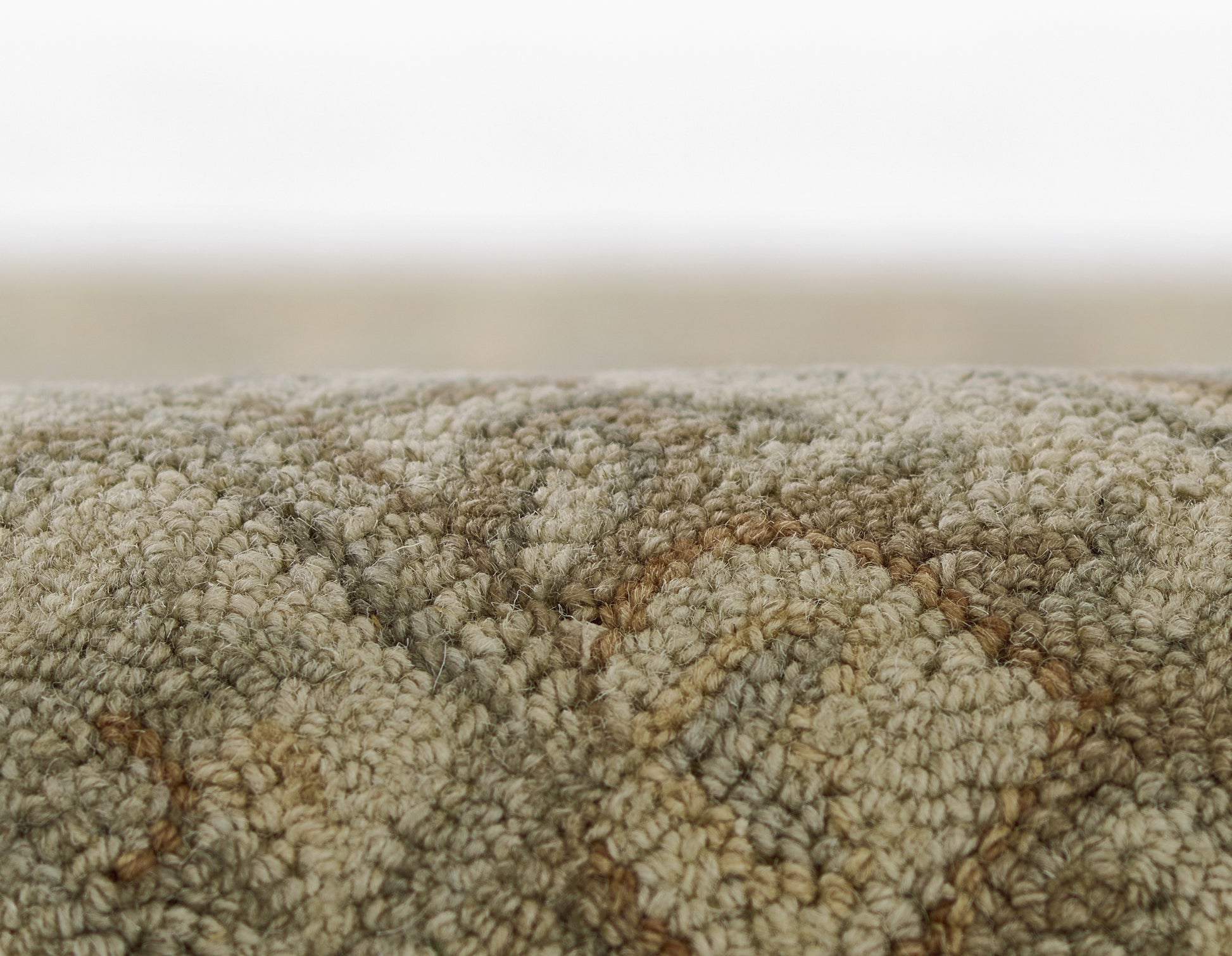Close-up of beige-gray rug with plush boucle pile and brown-toned diamond pattern.