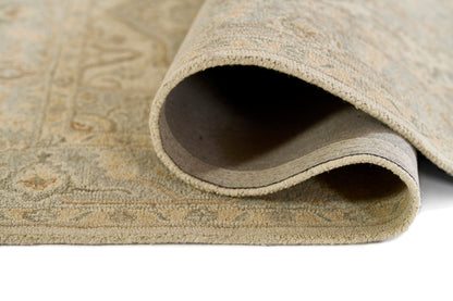 Beige patterned runner rug with a curled edge, showing the soft underside and a delicate traditional motif.