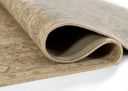 Beige taupe area rug rolled at edge, showing soft plush pile and subtle pattern.