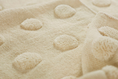 Cream plush fabric with raised circular tufted dots, cozy throw blanket.