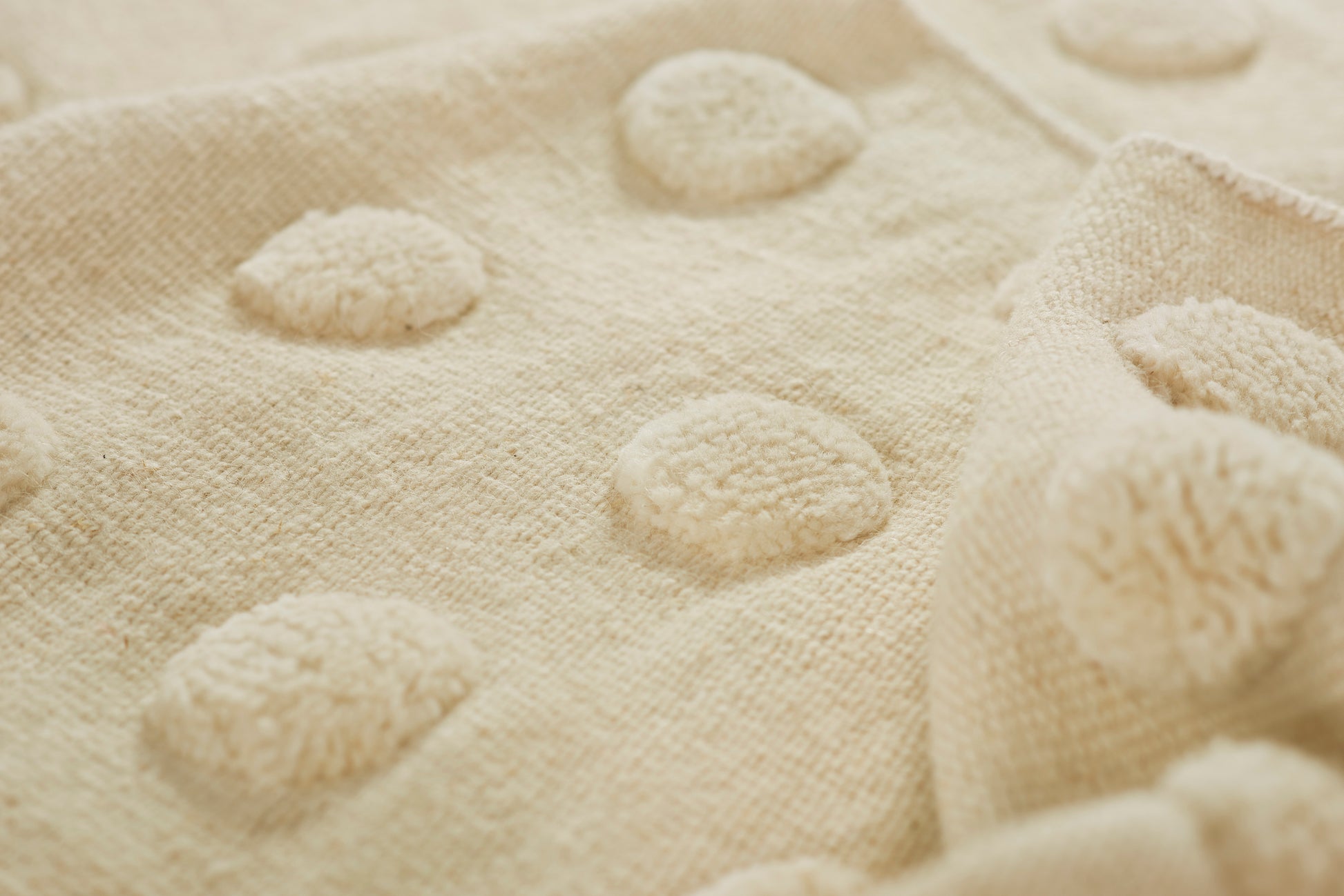 Beige plush fabric with raised circular dots creating a soft tufted polka-dot texture.