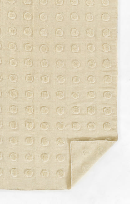 Beige linen-like rug with embossed circular dot pattern and folded corner.