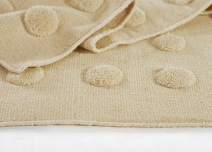 Beige boucle knit rug with raised round pom-pom dots; soft, cozy surface for living room or nursery (5' x 8').