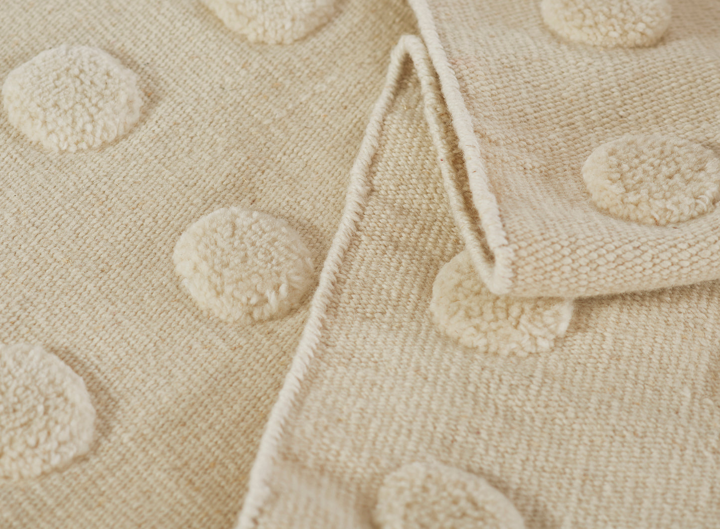 Beige rug with a raised pom-pom dot pattern.