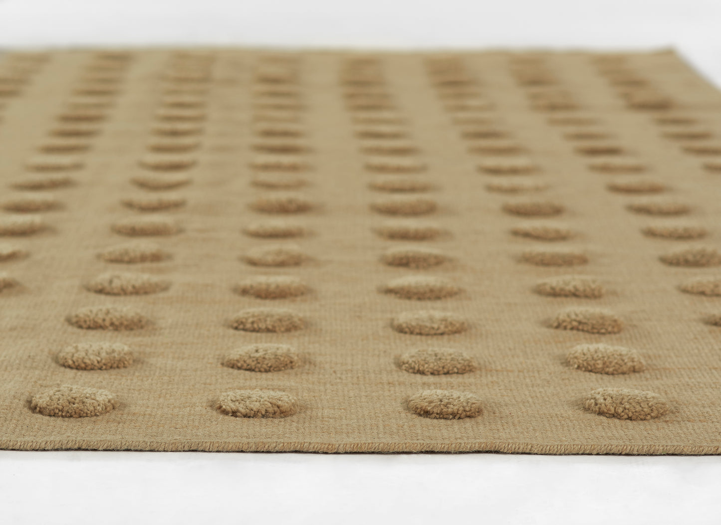 Beige woven rug with evenly spaced raised circular dot pattern; natural jute texture.