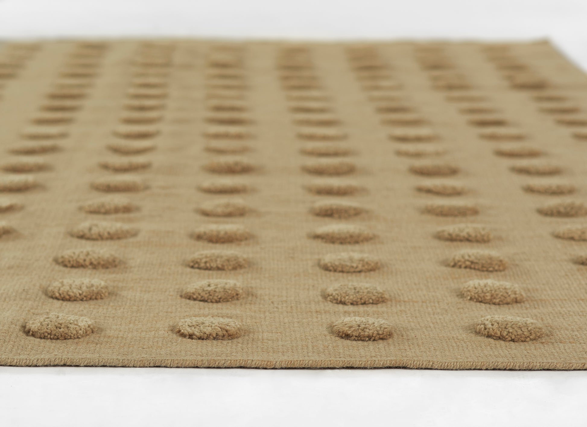Beige woven rug with evenly spaced raised circular dot pattern; natural jute texture.