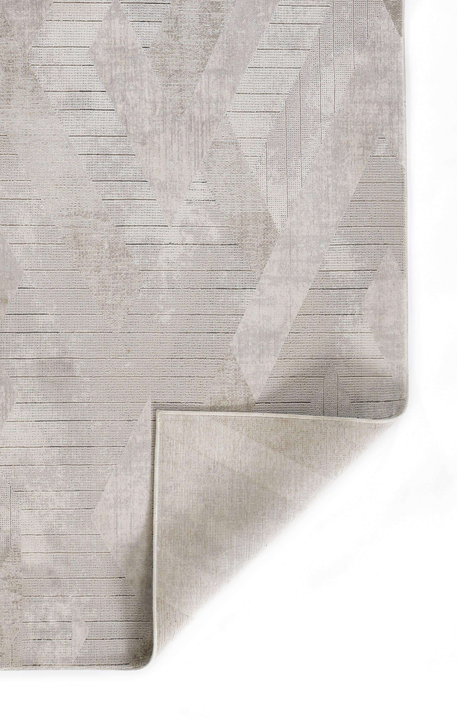 Grey textured rug swatch with subtle geometric pattern and folded corner.