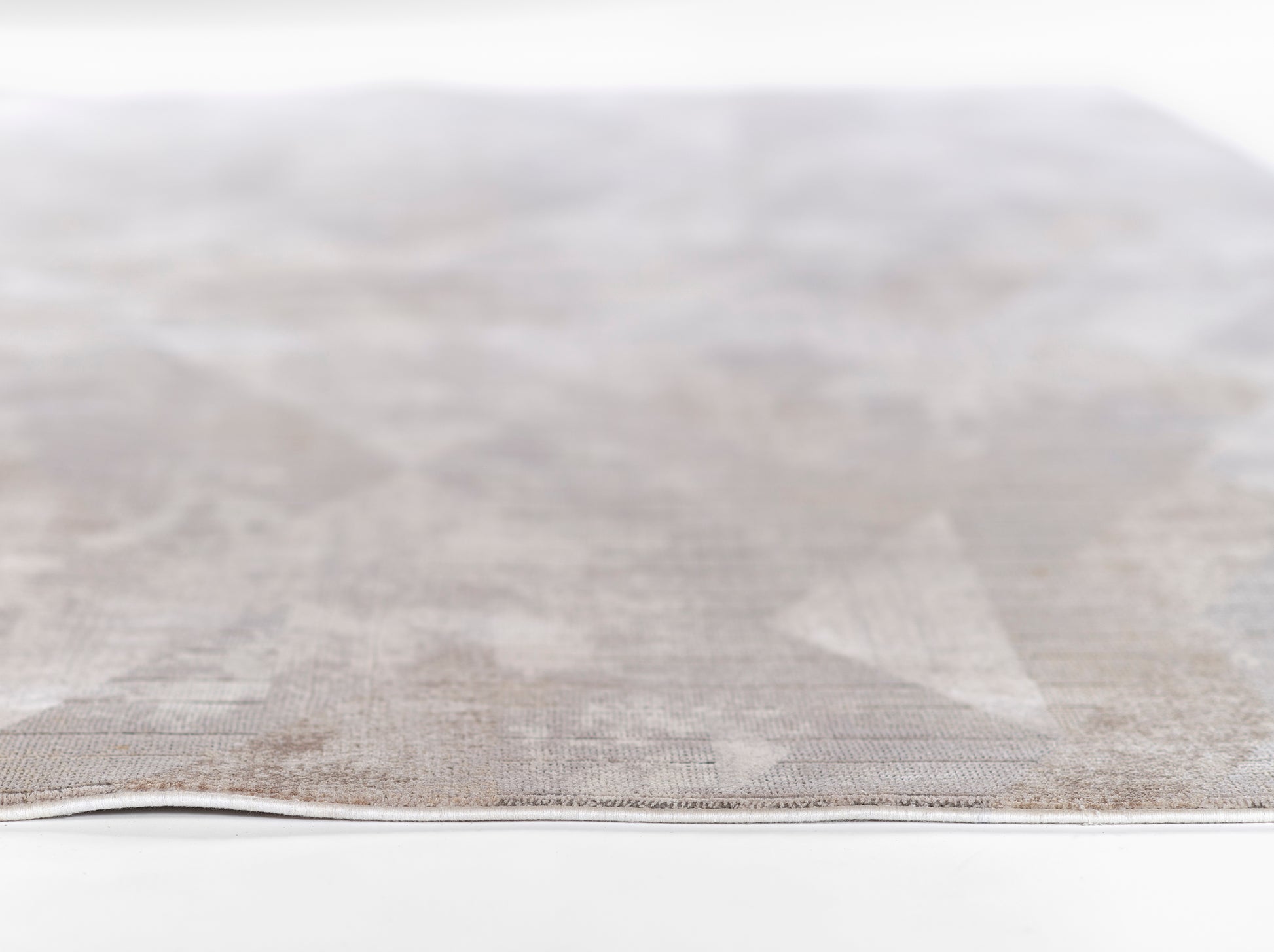 Light gray textured woven rug with subtle pattern; close-up edge, neutral home decor.