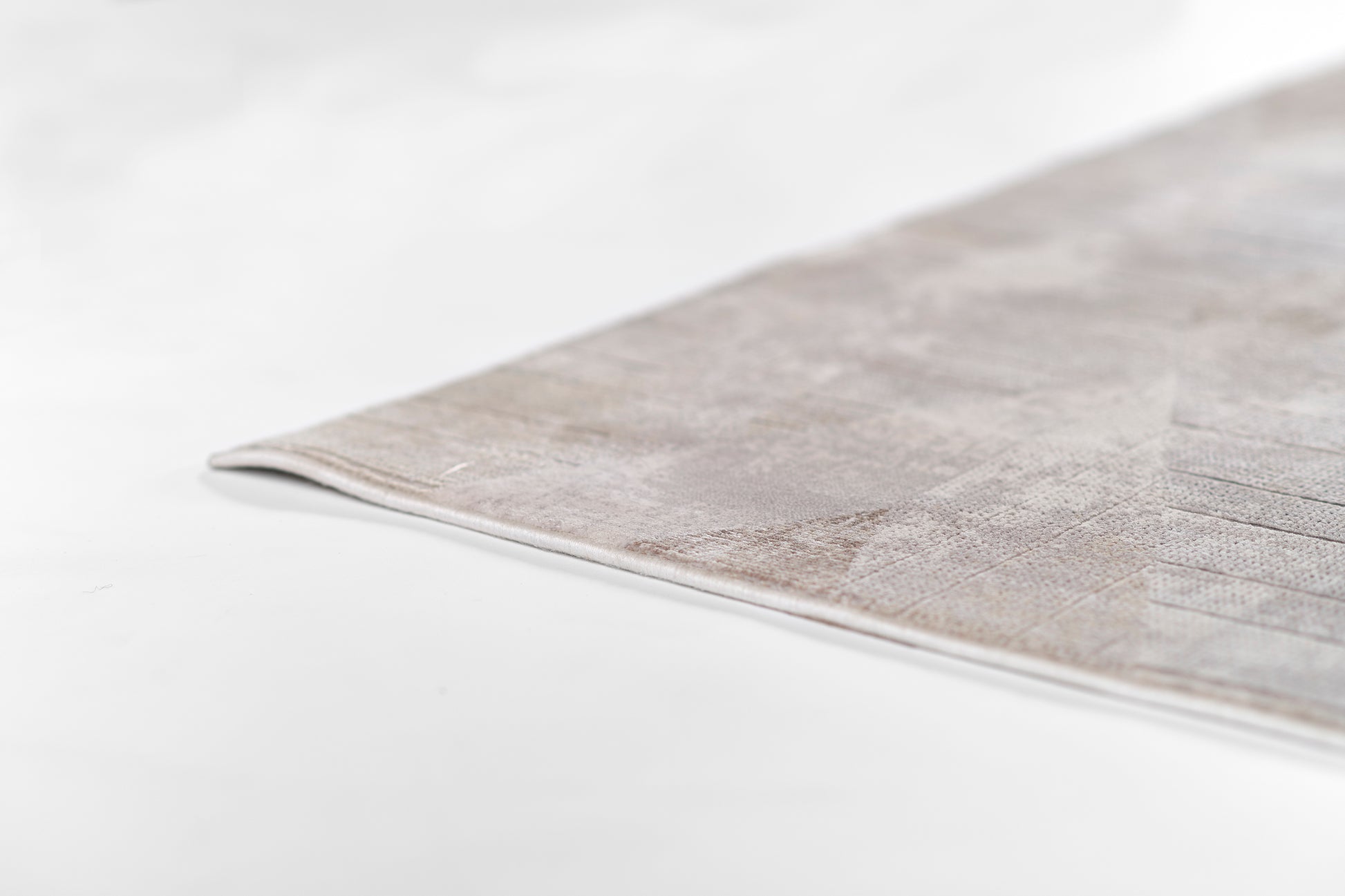 Gray flat-weave rug corner with subtle texture, modern minimalist living room decor.