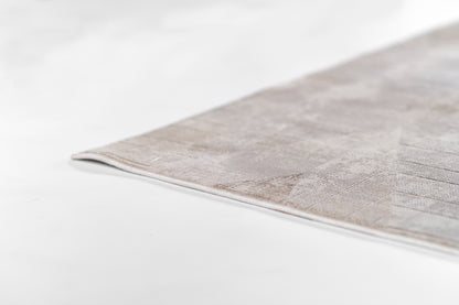 Gray flat-weave rug corner with subtle texture, modern minimalist living room decor.